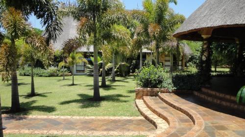 a park with palm trees and a building at Summerfield Botanical Garden & Exclusive Resort in Matsapha
