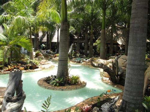 a swimming pool with palm trees in a resort at Summerfield Botanical Garden & Exclusive Resort in Matsapha