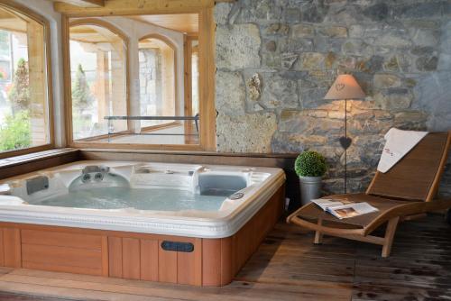 bañera de hidromasaje en una habitación con pared de piedra en Hotel-Spa Le Morillon Charme & Caractère, en Morillon