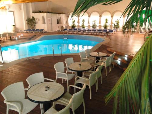 un restaurante con piscina, mesas y sillas en Hotel Miami, en Calella