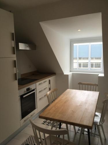 une cuisine avec une table et des chaises en bois ainsi qu'une fenêtre dans l'établissement La ville à la mer numéro 2 duplex en plein coeur du centre ville au calme terrasse et parking privé, à Concarneau