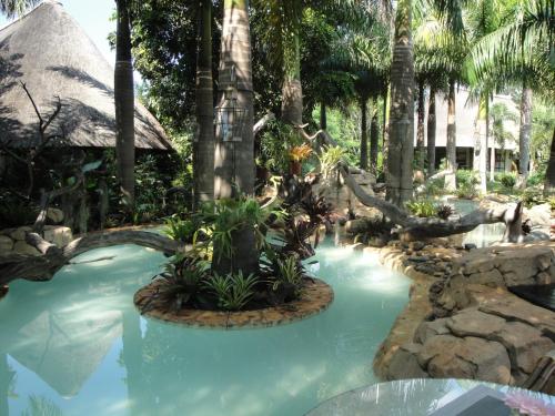 a swimming pool in a resort with palm trees at Summerfield Botanical Garden & Exclusive Resort in Matsapha