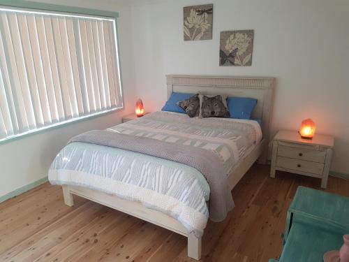 a bedroom with a large bed with two lamps on it at Paradise by the Beach - Culburra beach in Culburra Beach