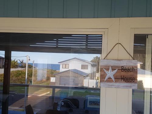 a window of a beach house with a sign on it at Paradise by the Beach - Culburra beach in Culburra Beach