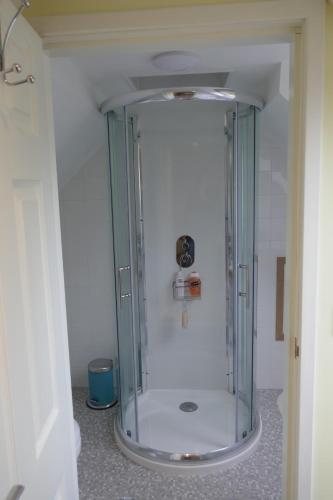 a shower with a glass door in a bathroom at The Den , Sengera in Inverness