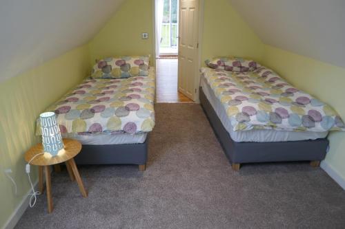 a bedroom with two beds and a table and a chair at The Den , Sengera in Inverness