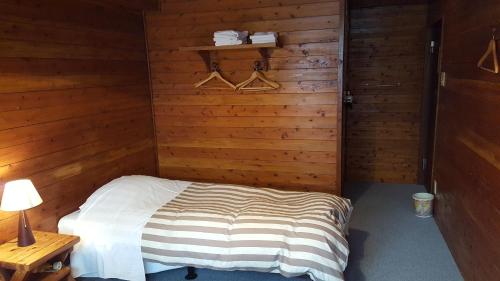 a bedroom with a bed in a wooden room at Pension Baden Heim in Nagasaki
