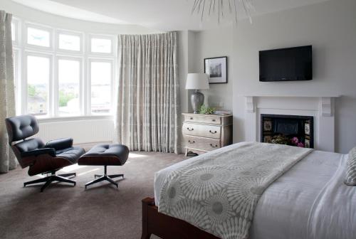 a bedroom with a bed and two chairs and a television at 2 Crescent Gardens Guest House in Bath