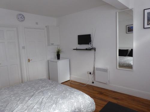 a bedroom with a bed and a tv on a wall at Soft & Bright in Thornton Heath