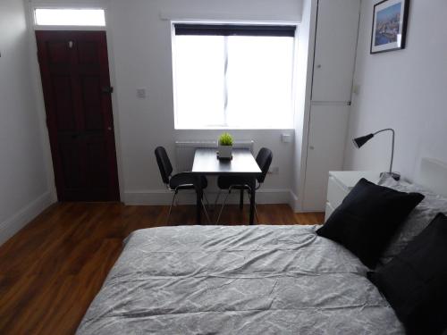 a bedroom with a bed and a table and a window at Soft & Bright in Thornton Heath