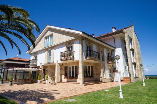 una gran casa blanca con una palmera en Hotel Don Pepe, en Ribadesella