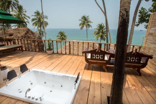 a bath tub sitting on a deck with the beach at The Cape Goa in Cabo de Rama