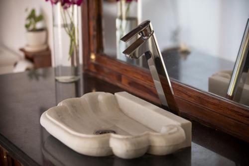 a bathroom sink with a faucet in front of a mirror at The Cape Goa in Cabo de Rama