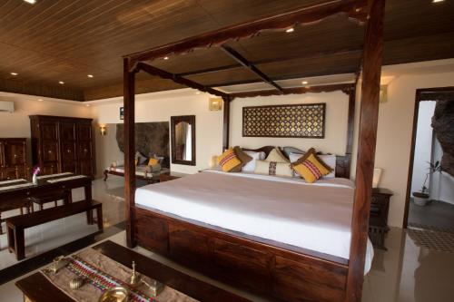 a bedroom with a large wooden bed and a desk at The Cape Goa in Cabo de Rama