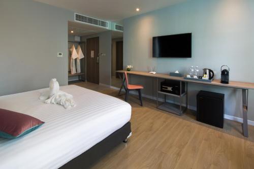 a bedroom with a bed and a desk with a television at Hotel Tranz in Bangkok