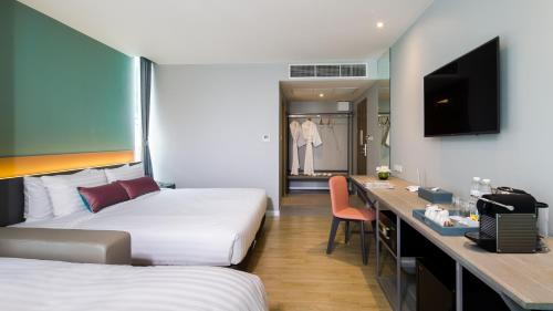 a hotel room with two beds and a desk at Hotel Tranz in Bangkok