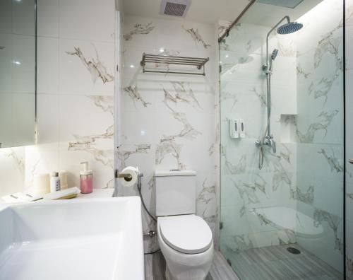 a white bathroom with a toilet and a shower at Hotel Tranz in Bangkok