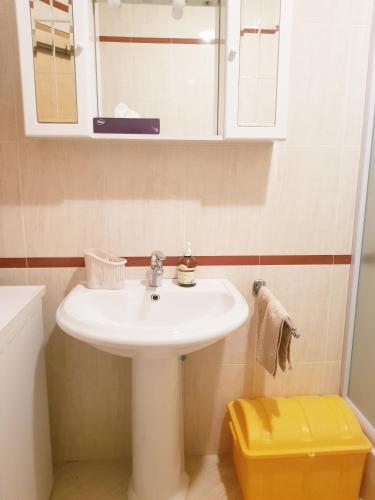 a bathroom with a white sink and a yellow stool at App LOLLY in Selce