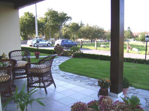 a patio with chairs and a lawn with cars on a street at Casa de Aldea El Frade in Ribadesella