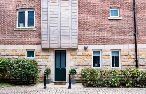 a brick building with a green door and some plants at Riverside Retreat - Durham in Durham