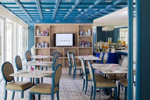 a dining room with tables and chairs and a tv at Hotel Tranz in Bangkok