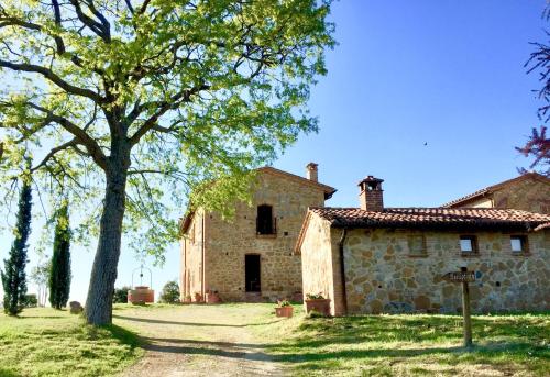 an old stone house with a tree in front of it at Locanda Vesuna Hotel Countryhouse in Pienza