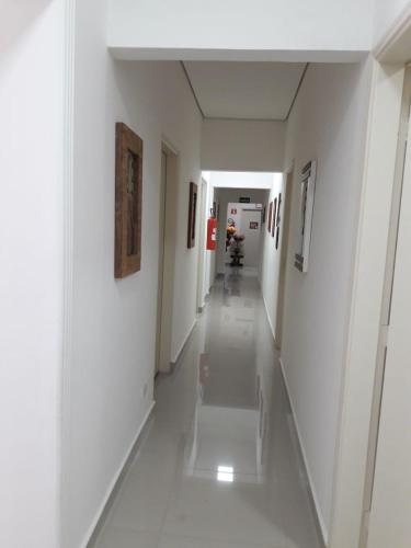 a hallway in a building with white walls and white floors at Hotel Morada do Mar in Guarujá