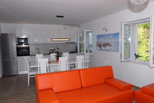 a living room with an orange couch and a kitchen at Villa Mambo in Mlini