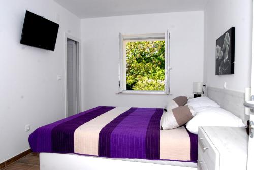 ein weißes Schlafzimmer mit einem Bett und einem Fenster in der Unterkunft Villa Mambo in Mlini