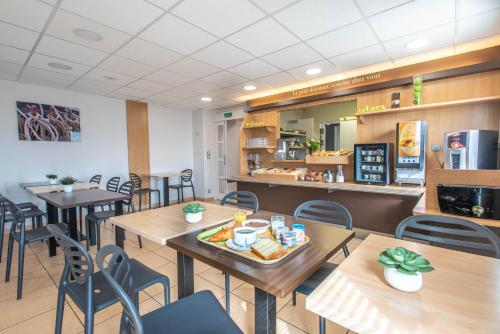 a restaurant with tables and chairs and a counter at B&B HOTEL Vannes Ouest Golfe du Morbihan in Vannes