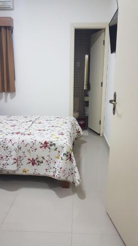 a bedroom with a bed with a floral comforter at Hotel Morada do Mar in Guarujá