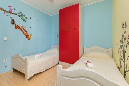 two beds in a room with a red cabinet at Apartman Kiara Hana in Split