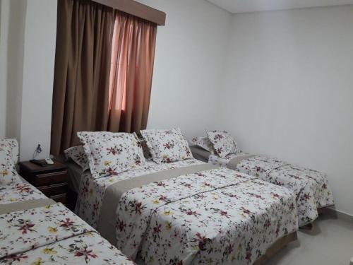 a bedroom with two beds and a window at Hotel Morada do Mar in Guarujá