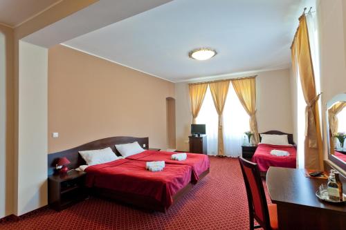 a hotel room with two beds and a table and a desk at Pałac Pawłowice in Gorz