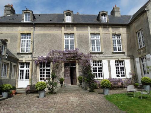 une vieille maison avec des couronnes violettes dans la cour dans l'établissement Hôtel particulier "le clos de la croix", à Bayeux