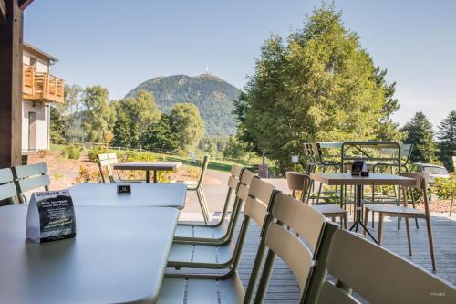 a patio with tables and chairs and a view of a mountain at Archipel Volcans in Saint-Genès-Champanelle