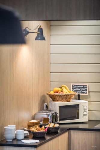a kitchen with a microwave and a basket of fruit at Archipel Volcans in Saint-Genès-Champanelle