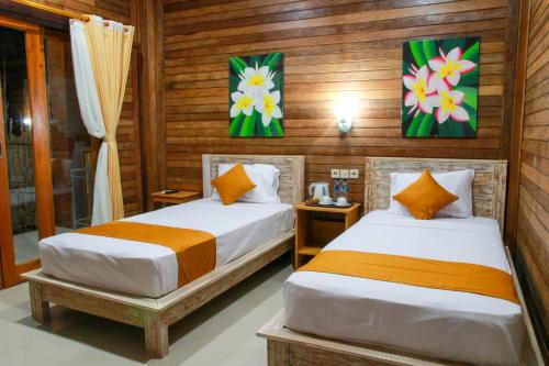 two beds in a room with wooden walls at D'Tegal House in Nusa Lembongan