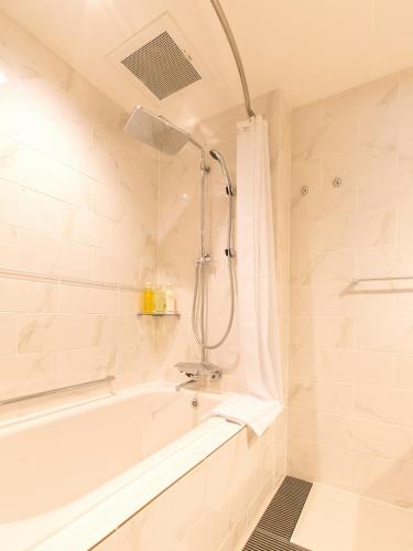 a white bathroom with a tub and a shower at Hotel Shiki Utsubo Park in Osaka