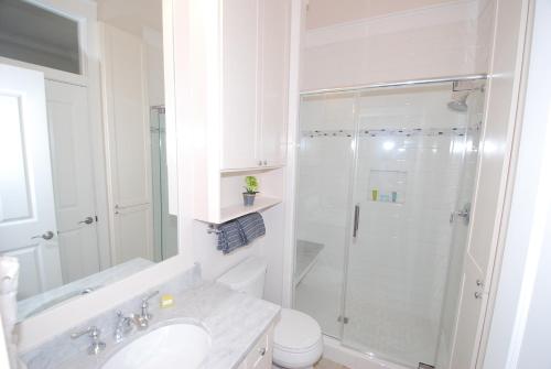 baño blanco con ducha y lavamanos en Coastal Home en South Padre Island