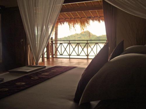 a bedroom with a view of the ocean and a balcony at Lombok Villas, Villa KuraKura in Labuhanpoh