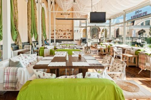 a restaurant with green tables and chairs and a tv at Boutique Hotel Traditional in Astana