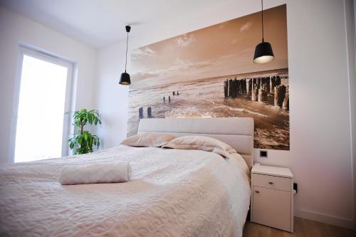 a bedroom with a bed with a painting on the wall at Apartament Widok Na Morze 17 piętro 4 Oceany in Gdańsk