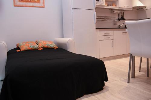 a bedroom with a bed with a black blanket and a kitchen at JAK Colón in Colón