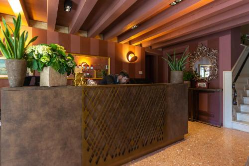 a person sitting at a counter in a restaurant with plants at Hotel Tiziano in Venice