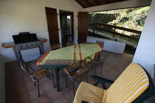 une terrasse avec une table, des chaises et une cuisinière dans l'établissement La Maison Verte, à Les Plantiers