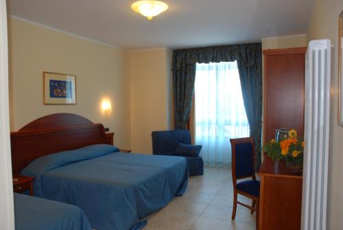 a bedroom with two beds and a chair and a window at Hotel Duca Di Calabria in Serra San Bruno