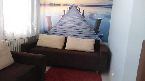 a room with a couch and a painting of a pier at Apartament Nad Czosem in Mrągowo