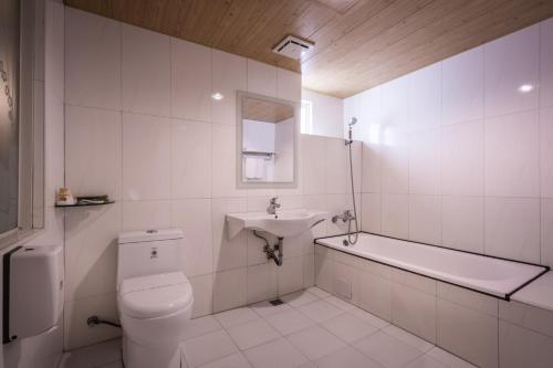a white bathroom with a toilet and a sink at Golden Phoenix Hotel in Kaohsiung