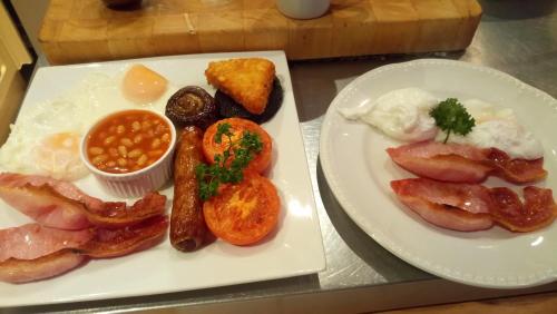 two plates of breakfast foods with eggs bacon beans and beans at Camellia Lodge Guest House in Weston-super-Mare